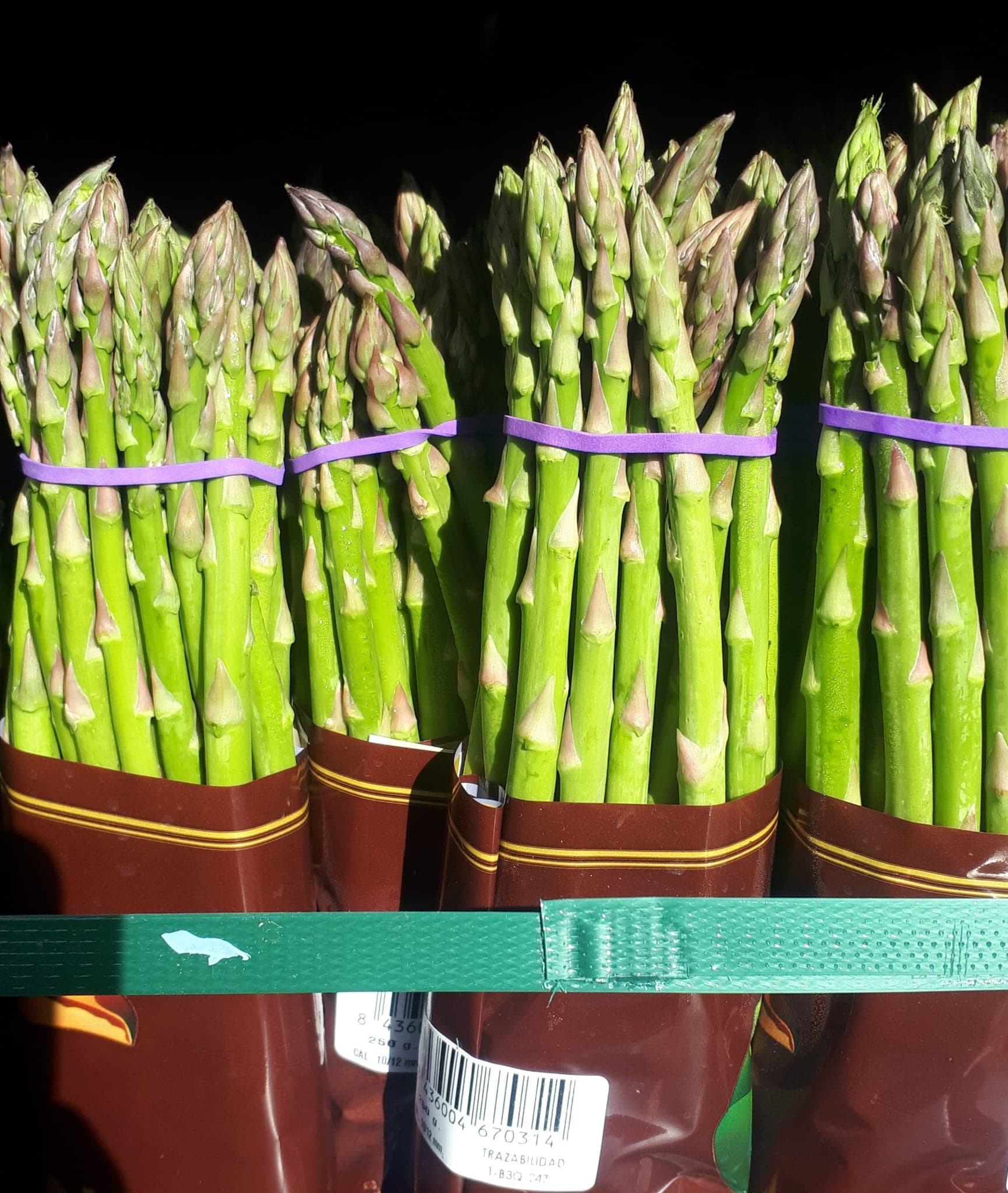 Manojos de espárragos verdes atados y presentados en expositor vertical